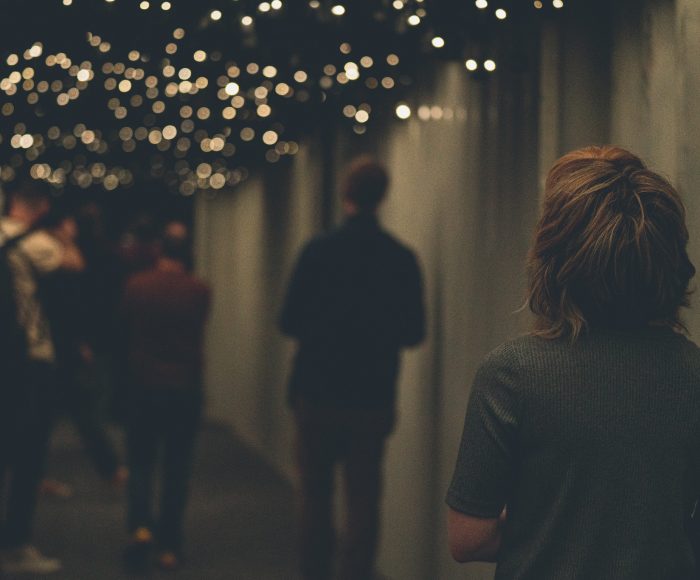 A group of people walk through a dimly lit corridor where tiny speakers with lights line the roof